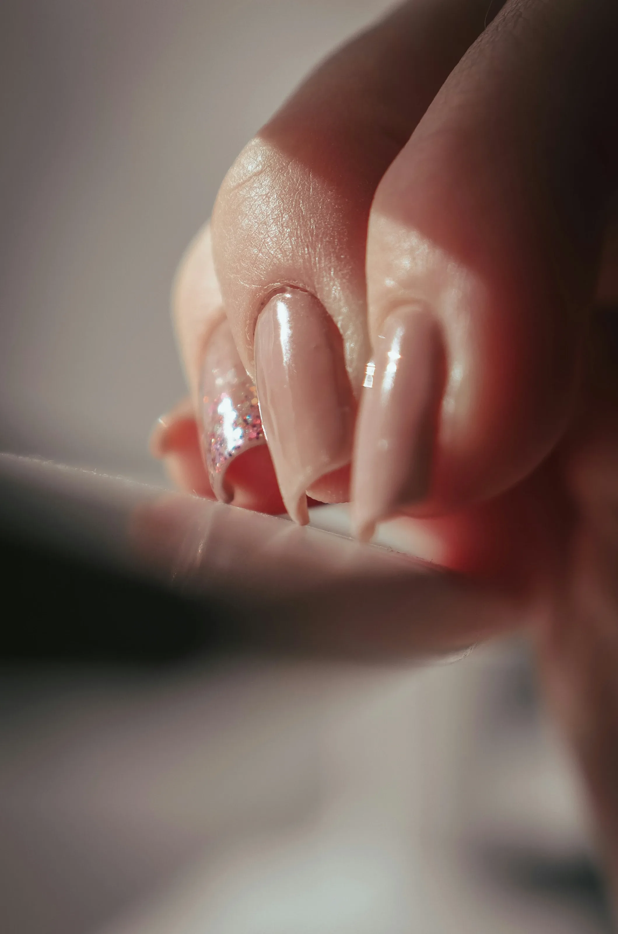Close-up of long, glossy nude nails during a manicure