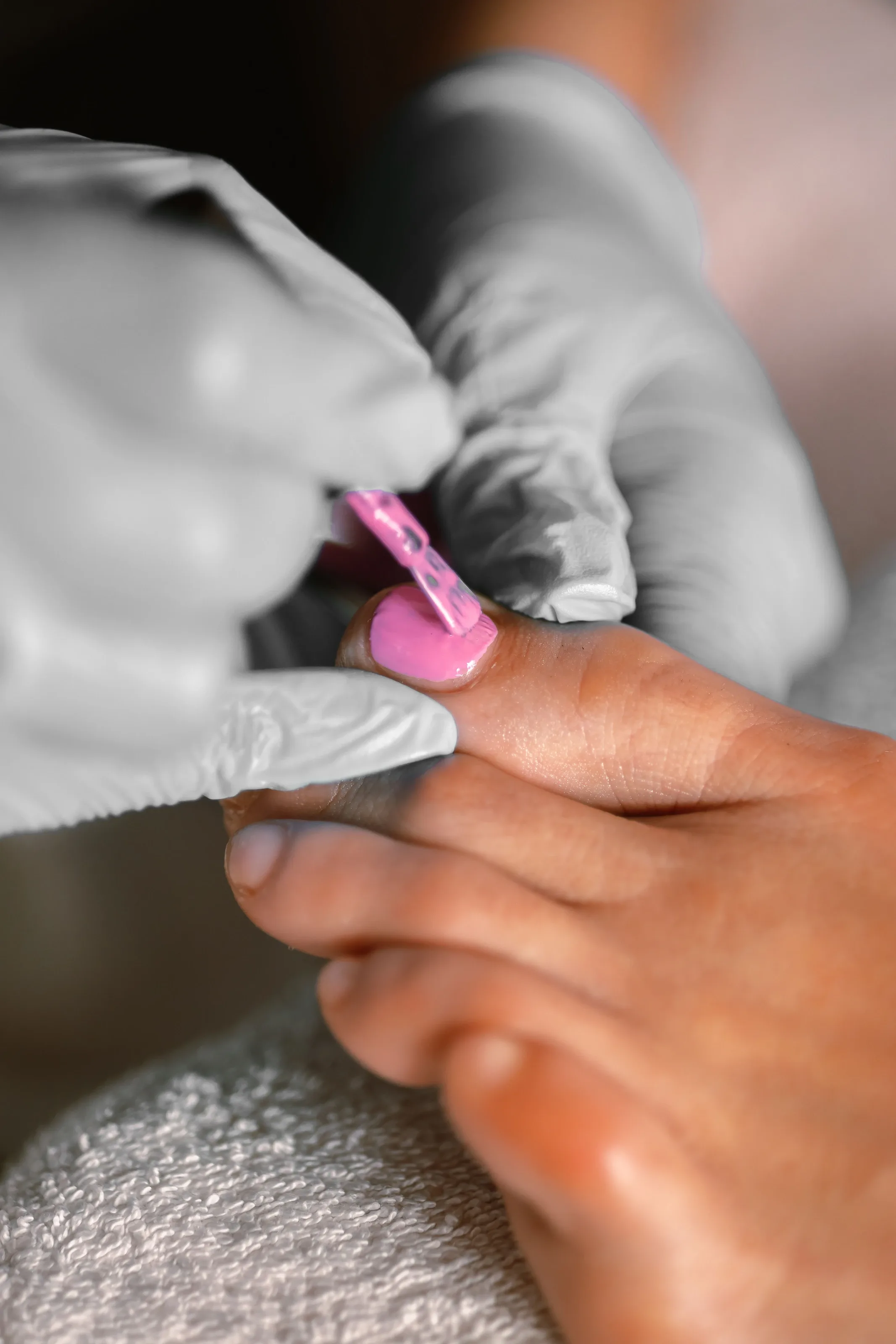 Nail technician painting toenails a bright pink during a pedicure