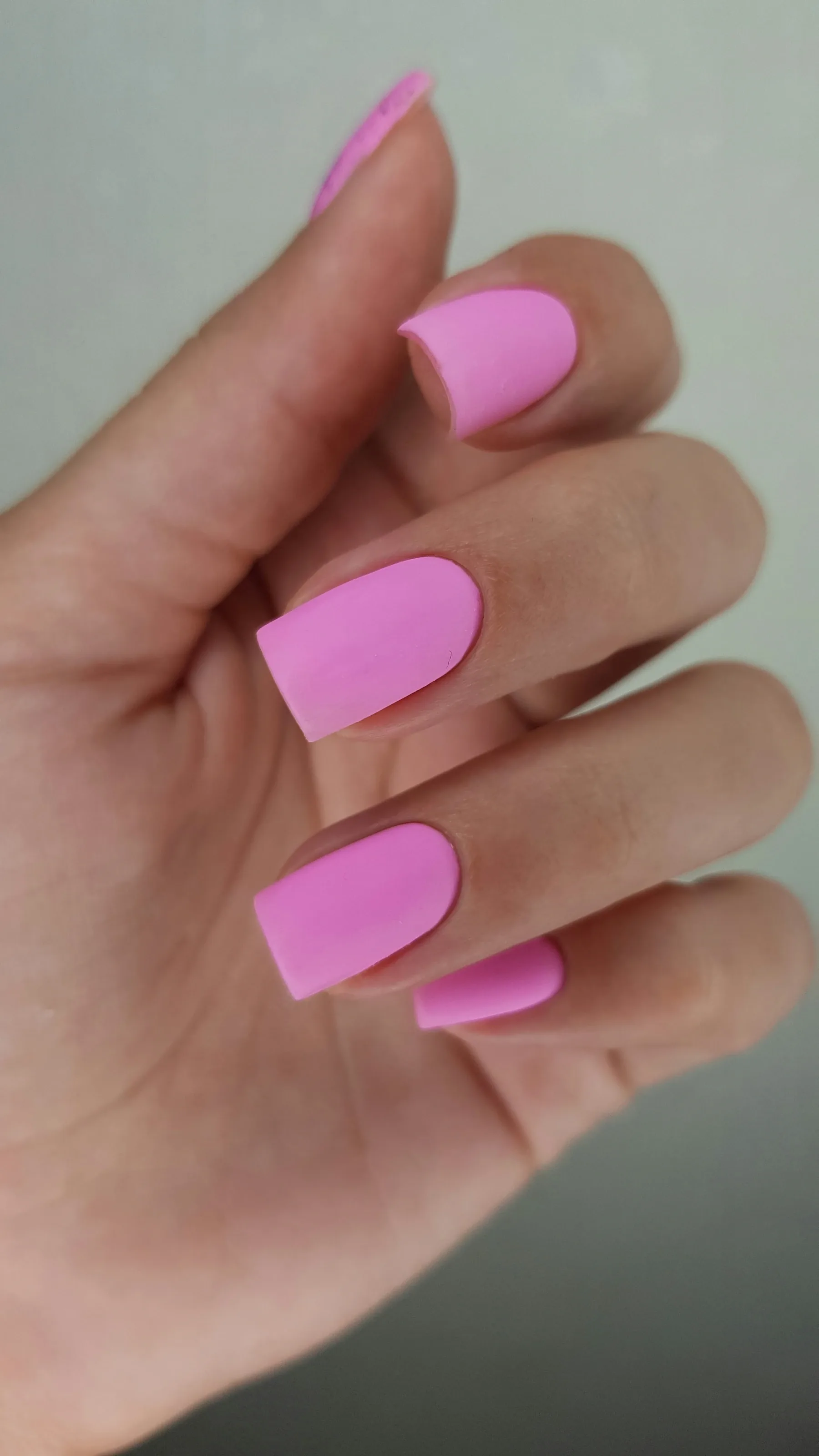 Square nails painted in a bright matte pink